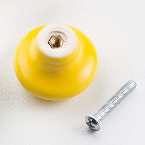 Hella Stylish Yellow Ceramic Knobs And Round Drawer Pulls For Kitchen Cabinets And Dressers Featuring Heavy Duty Zinc Alloy Backing Kid Friendly Curved Shape Tough As Nails Scratch Resistant Finish Make Your Home Decor Pop Set Of Four. Close-up image of yellow ceramic knob and screw.