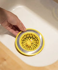 Hand placing Quack Duck Kitchen Sink Strainer Basket Fits All Standard Sinks 4 And A Half Inch Stainless Steel Drain Cover With Bright Yellow Duck Design