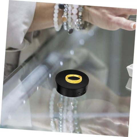 Compact Electric Rotating Turntable Stand For Jewelry Display, 360 Degree Silent Base showcasing a gold ring on a glass surface.