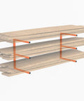 Garage Wall Mounted Lumber Storage Rack For Woodworking Shop Overhead Heavy Duty One Piece Design Keeps Lumber Off The Floor And Neatly Organized Space Saving Solution For A Pair Of Racks showing orange metal brackets holding wood planks.