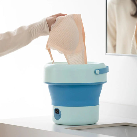 Hand placing delicate items into a Foldable Mini Washing Machine 4.8 Liter Portable Compact Laundry Soaker for quick rinse.