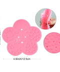 Pink silicone flower-shaped scrubber with dimensions shown, featuring close-up of flexible material and textured surface.
