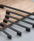 Assorted sizes of matte black zinc alloy cabinet pulls and furniture handles 1 pair displayed on a wooden surface.
