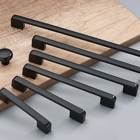 Assorted sizes of matte black zinc alloy cabinet pulls and furniture handles 1 pair displayed on a wooden surface.
