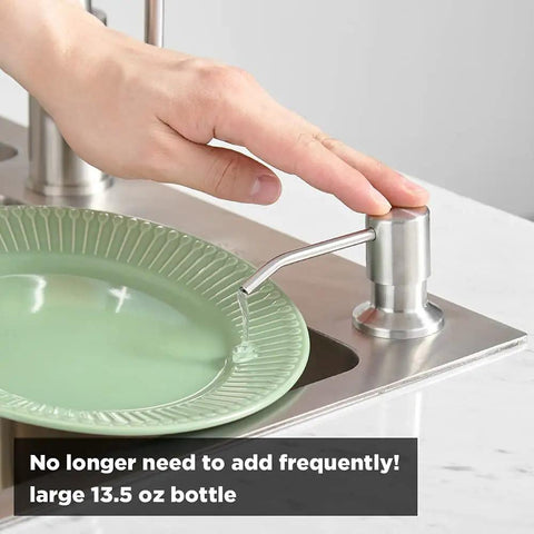 Person using Stainless Steel Built In Kitchen Soap Dispenser With Brushed Nickel Finish Top Refill Design Large Thirteen Point Five Ounce Bottle Durable 304 Stainless No Drips Easy Refill From The Top Slick Modern Sink Accessory beside green plate