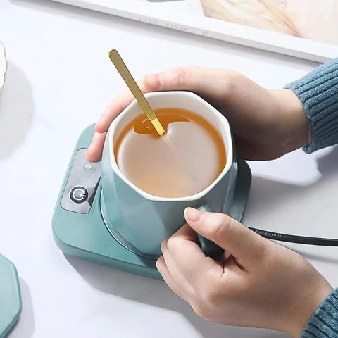 Smart Electric Cup Warmer Keeps Your Daily Coffee Brew Toasty With Rapid Heat Plate And Steady Temperature Lock, hand holding teal mug.
