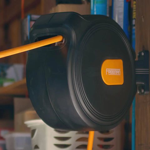 Compact Retractable Air Hose Reel With Brass Fittings And Mounting Bracket One Quarter Inch By Sixty Five Feet Spring Powered Lead Hose Included Durable Hybrid PVC Hose For Easy Shop Or Garage Air Access mounted on a garage wall