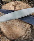 Two Cow Scythe Sharpening Stone With One Eighty Grit Silicon Carbide Wet Stone For Scythes Nine Inch Long One And Three Eighths Inch Wide Five Eighths Inch Thick Made In Austria Great For Home Use And Farm Work on tree stump