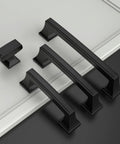 Set of matte black cabinet handles and single knob on a light background, featuring the 10 Pack 1.4 Inch 35mm Matte Black Cabinet Knobs for Kitchen Cabinets and Dressers, Zinc Alloy Drawer Hardware for Dresser Drawers and Furniture Renovation.