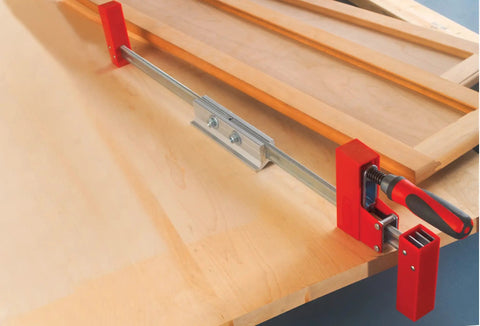 K Body REVO Extender for Dual Clamp Sets connects two clamps to extend reach on woodworking surface, aluminum construction visible.