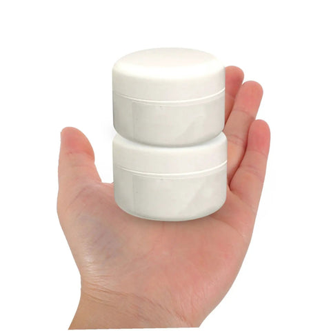 Hand holding two white jars from Two Pack Ceramic Repair Paste Kit For Tiles And Porcelain Restoration Fast Dry Formula To Fix Chips Scratches And Dents At Home DIY Friendly Indoor Tile Repair For Kitchens Bathrooms And Other Surfaces.