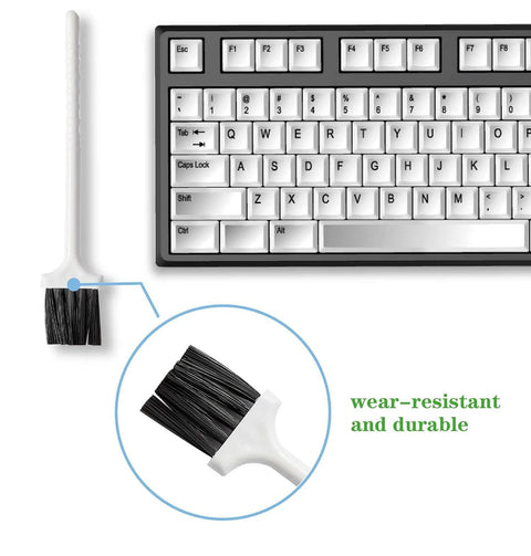 Keyboard cleaning brush with white handle and black bristles beside a mechanical keyboard; close-up of bristles