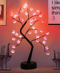 Cherry Blossom Tree Lamp For Living Room Decor And Cozy Night Light, DIY Artificial Tree Light For Home Weddings Christmas And More, USB Or Battery Powered Ambience showing pink LED blossoms on a black trunk on a tabletop.