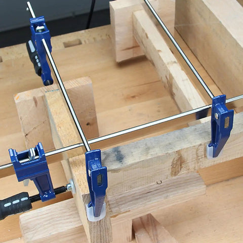 Professional Grade Eighteen Inch F Clamp Boasts A Smooth Quick Release Lever applied on wooden boards for secure gripping.