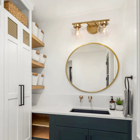 Two-Light Gold Vanity Light With Clear Globe Glass Shades Over-Mirror Fixture In Hand-Painted Gold Finish in bathroom setting