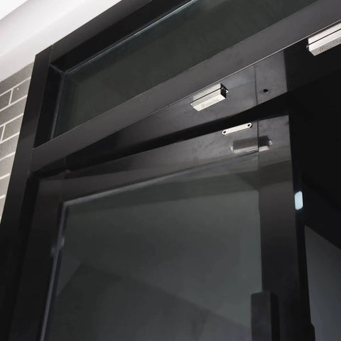 Heavy Duty 70lb Magnetic Door Catch For Stainless Steel Cabinets And Drawers installed on a glass door in a modern setting.