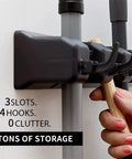 Wall Mount Mop And Broom Holder With 3 Slots And 4 Hooks, hand placing broom in the organizer