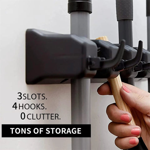 Wall Mount Mop And Broom Holder With 3 Slots And 4 Hooks, hand placing broom in the organizer