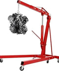 Shop Essential Two Ton Hydraulic Engine Hoist With Six Swivel Rollers And Quick Fold Frame lifting an engine, red steel construction, storage-friendly design.
