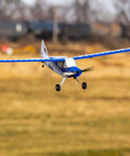Blue and white Sport Cub S 2 RC Airplane BNF Basic with safe technology flying outdoors on a grassy field