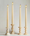 Four lit 12 Pack Ivory Flameless LED Taper Candles, 11 Inch Tall, Battery Operated With Bottom On Off Button in candle holders