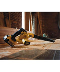 20V Max Cordless Leaf Blower with 100 CFM airflow resting in a workshop, lightweight design with 3 nozzle attachments, trigger lock visible