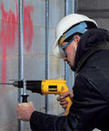 Worker using a Power Through Concrete And Wood With A 1/2 Inch Hammer Drill, 7.8 Amp Heavy Duty on concrete wall