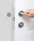 Close-up of a hand gripping a silver door handle on a white door with a blue furniture slider for protection.