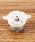 12V Tiny Gearbox DC Motor With 3 RPM Slow Speed High Torque 4mm Shaft Reversible Low Noise on wooden surface