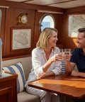 Couple enjoying drinks with Make Fresh Water From Air With This Atmospheric Water Generator, No Plumbing Or Tap Water Needed, Purified 2.64 Gallons For Home, RV, Boat, Off-Grid Or Emergency Use, Just Plug In And Sip Clean Water Anywhere on table in a boat cabin