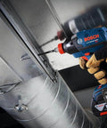 Bosch cordless drill with drill bit in metal duct, blue body and orange trigger