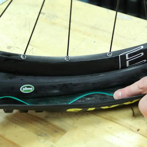 Close-up of bike tire with inserted protector for Bike Tire Liners And Protectors Lightweight Puncture Proof Set For 12 to 26 Inch Tires Fits One And A Half to Two And An Eighth Inches Width Keeps Nails And Debris Out Between Tube And Tire For Two Tires Easy Install.
