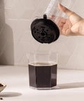 High Performance Flow Control Filter Cap For Manual Coffee Brewers Delivers Complete Brew Command with coffee being poured.