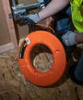 Professional Grade 200 Foot Non Conductive Fiberglass Fish Tape Featuring Multi Groove Low Friction Design And 500 Pound Pull Rating For Zero Stress Wiring Hustle in use by electrician.