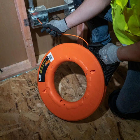 Professional Grade 200 Foot Non Conductive Fiberglass Fish Tape Featuring Multi Groove Low Friction Design And 500 Pound Pull Rating For Zero Stress Wiring Hustle in use by electrician.