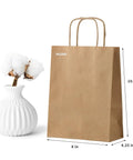 50 Pack Go-To Brown Kraft Paper Bags With Handles 8x4.25x10.5 Inches Heavy-Duty Gift Bags for party favors next to white vase.