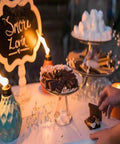 Decorative Glass Table Torch With Durable Fiberglass Wick And Metal Snuffer Creates Cozy Ambience For Dining Or Desk Decor Burns Up To Six Hours Per Fill A Thoughtful Holiday Gift For Family And Friends next to dessert display.