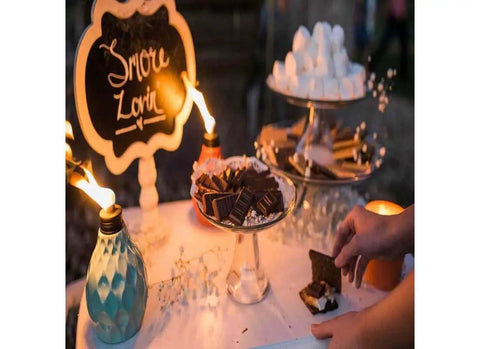 Decorative Glass Table Torch With Durable Fiberglass Wick And Metal Snuffer Creates Cozy Ambience For Dining Or Desk Decor Burns Up To Six Hours Per Fill A Thoughtful Holiday Gift For Family And Friends next to dessert display.