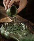 Hand pouring water from a green cup onto the Top Shelf Glazed Ceramic Tea Tray With Retro Textured Finish.