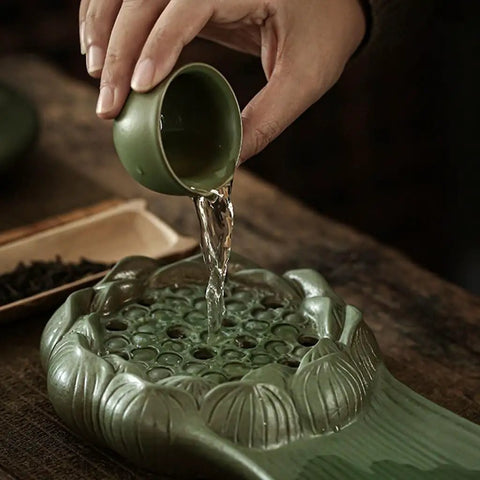 Hand pouring water from a green cup onto the Top Shelf Glazed Ceramic Tea Tray With Retro Textured Finish.