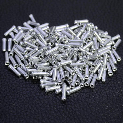 Alloy Cable End Caps 100Pcs Silver For Road And Mountain Bike Cables, shown in a pile on a black surface.
