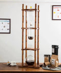 Premium Gravity Fed Cold Brew Coffee Maker With Slow Drip Ice Tower And Zero Fuss Borosilicate Glass Carafe on wooden stand.