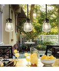 Lyndon 11.75 Inch One Light Pendant in Architectural Bronze With Clear Seeded Glass hanging over patio dining area