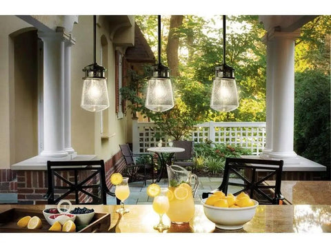 Lyndon 11.75 Inch One Light Pendant in Architectural Bronze With Clear Seeded Glass hanging over patio dining area