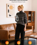 Person holding Portable 450W Plug In Heater With Remote, Clear LED Display, standing in living room with modern decor.