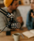 Professional microphone setup on table with blurred conversation in background; M6 Female To One Quarter Inch Male Tripod Screw Adapters Set Of Four