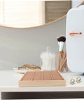 Totally Game Changing Wood Jewelry Tray With Plush Suede Grid Organization Board Featuring 40 Dedicated Spaces For Rings Bracelets And Daily Makeup Essentials Makes A Sweet Home Decor Gift on a dresser with earrings and makeup tools.