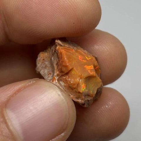 Hand holding Raw Fiery Jalisco Mexican Fire Opal Stone For Jewelry Making Multicolor Natural Opal Rough Gem with vivid fire play
