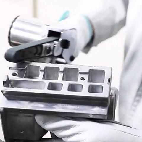 Shop Floor Ready Air Powered Handheld Belt Sander With Stepless Speed Control And Hassle Free Zirconia Strip Swap For Crushing Serious Wood Metal Stone Projects Today, close-up of sander in use on metal.