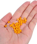 Hand holding 100 Pack Miniature Plastic Bushings and Axle Sleeves for Toy Vehicles, showing orange color and smooth low friction design.